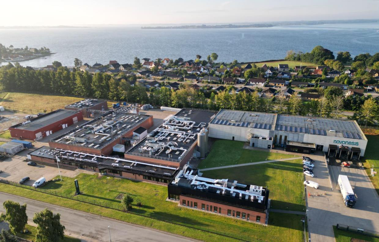 Luftfoto af Novonesis enzymfabrik på Sundsnæs i Gråsten med Flensborg Fjord i baggrunden