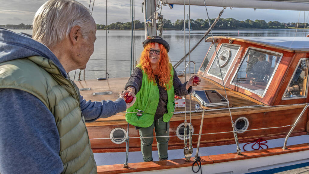 Æbledronningen Karin Baum rækker et æble ud fra skibet Viking af Gråsten til en gæst på kajen