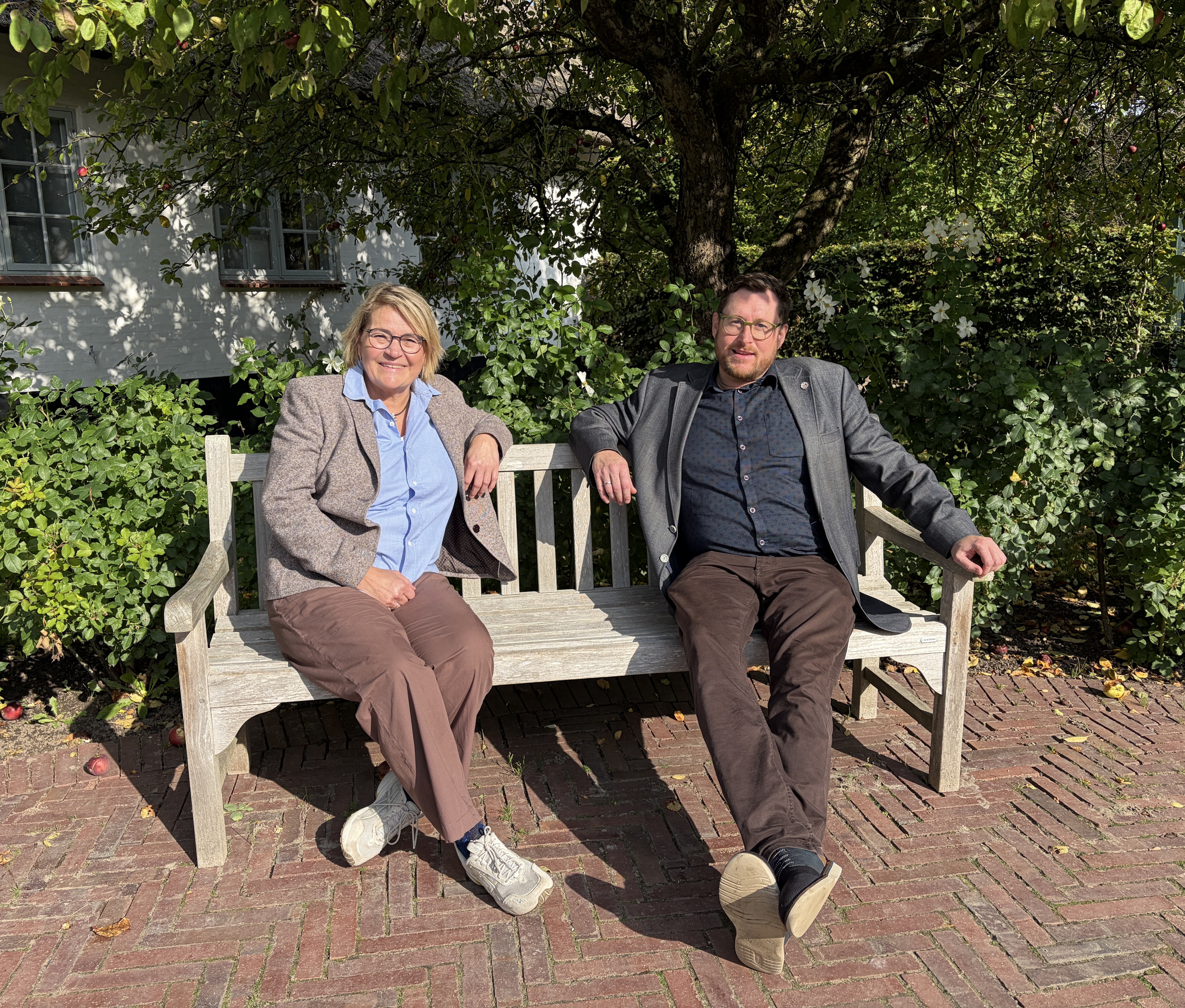 Ingrid Johannsen og Daniel Staugaard sidder på en bænk under træerne i Gråsten