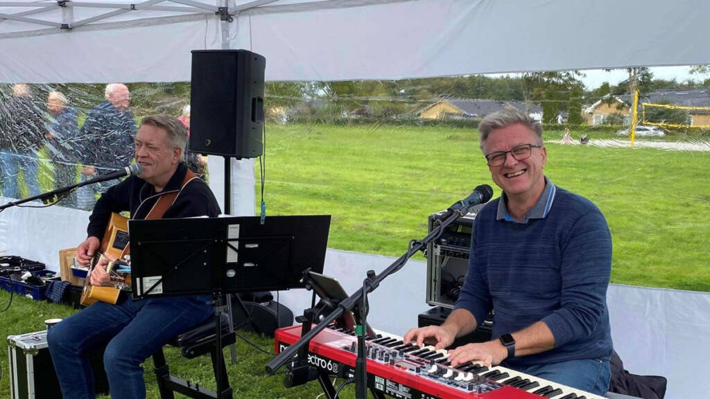 Peter og Preben spiller guitar og keyboard under et telt i Fritidsparken