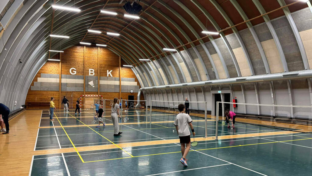 Børn og voksne spiller badminton i hallen hos Gråsten Badmintonklub
