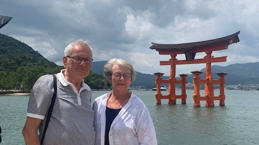 Ægtepar foran den flydende torii-port ved Itsukushima-helligdommen i Japan