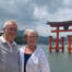Ægtepar foran den flydende torii-port ved Itsukushima-helligdommen i Japan