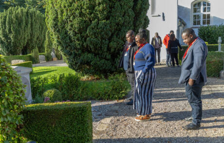 Gæster fra Tanzania går mellem hækkene ved kirken i Rinkenæs