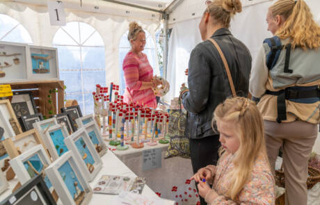Gæster kigger på billeder og kunsthåndværk i en bod på Gråsten Æblefestival