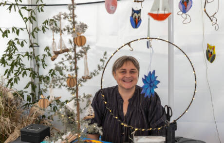 Kunsthåndværker med ophængte glasfigurer i sin bod på Gråsten Æblefestival