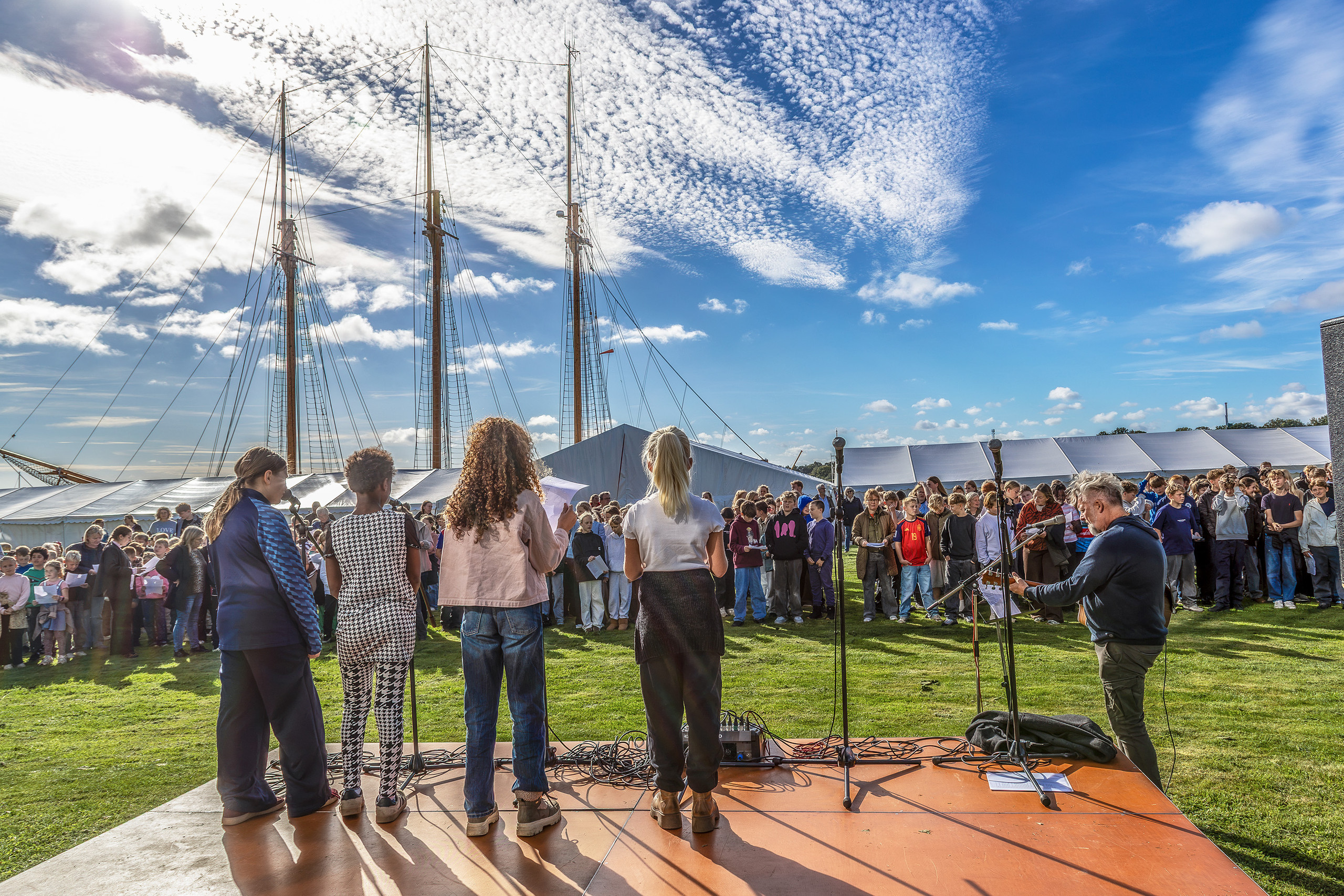 250 skoleelever sang ved Æblefestivalen (2) Skolebørn synger på scenen med skibsmaster og publikum i baggrunden ved Gråsten Havn