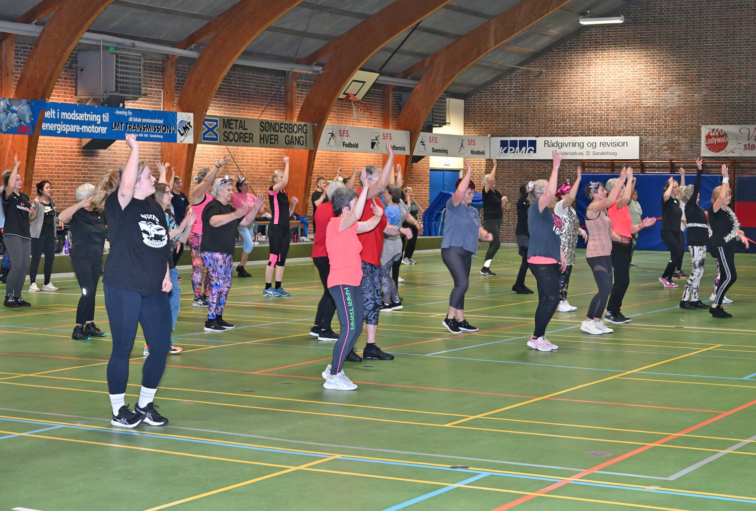 Dansere i sportstøj danser sammen på gulvet i en idrætshal