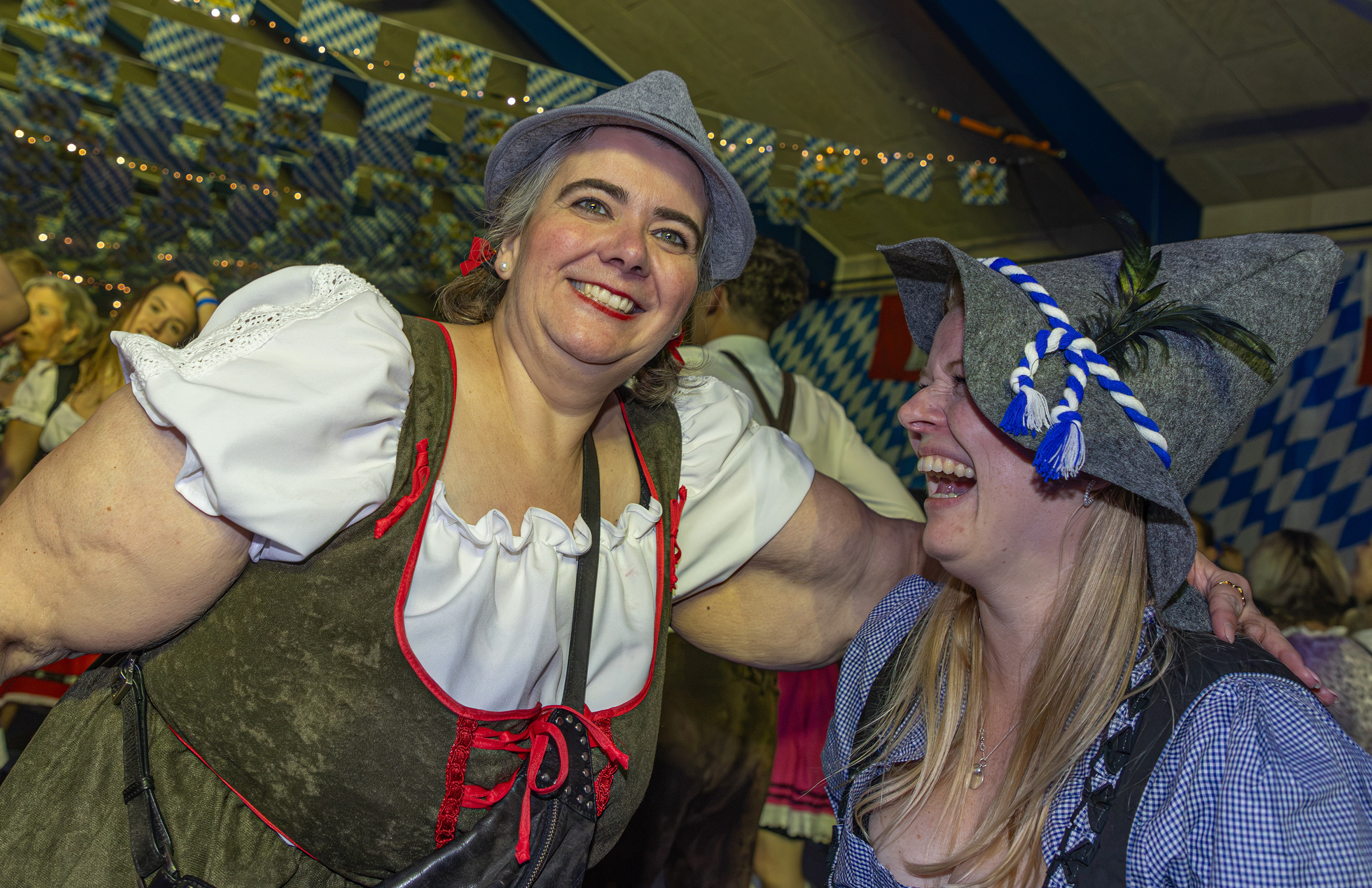 To leende kvinder i dirndl-kjole og filthat omfavner hinanden midt i festen til Bierfest
