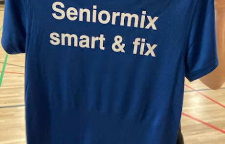 Parkour og crossfit hitter i Gråsten – billede 6 En kvinde holder en blå T-shirt med teksten Seniormix smart og fix op foran sig