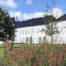 Det hvide Gråsten Slot bag et bed med røde blomster under blå himmel