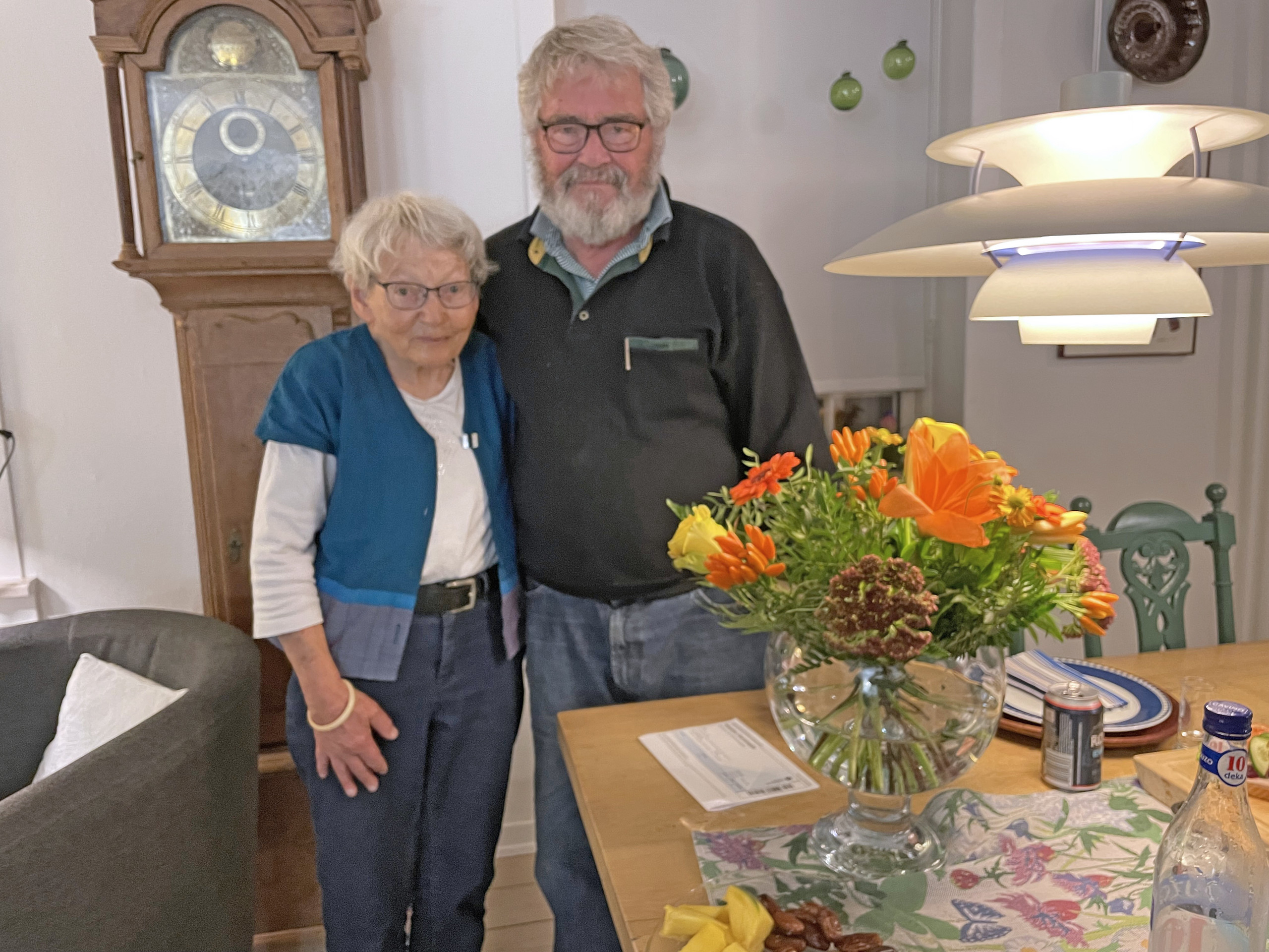 Kirsten og Erling Qvist står side om side i deres stue ved en buket efterårsblomster