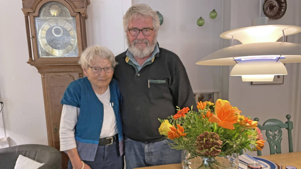 Kirsten og Erling Qvist står side om side i deres stue ved en buket efterårsblomster