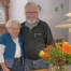 Kirsten og Erling Qvist står side om side i deres stue ved en buket efterårsblomster