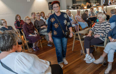Mode, hygge og fuldt hus (7) Model i mørk mønstret cardigan og jeans går mellem gæsterne ved modeopvisningen