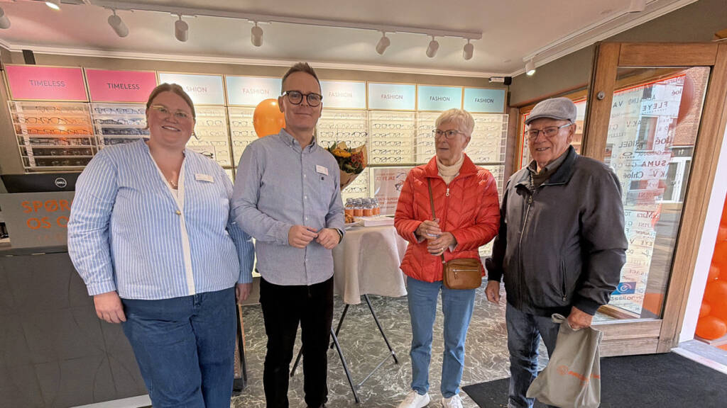 Fire personer står smilende foran en butiksdisk i den nyrenoverede optikerbutik Profil Optik i Gråsten