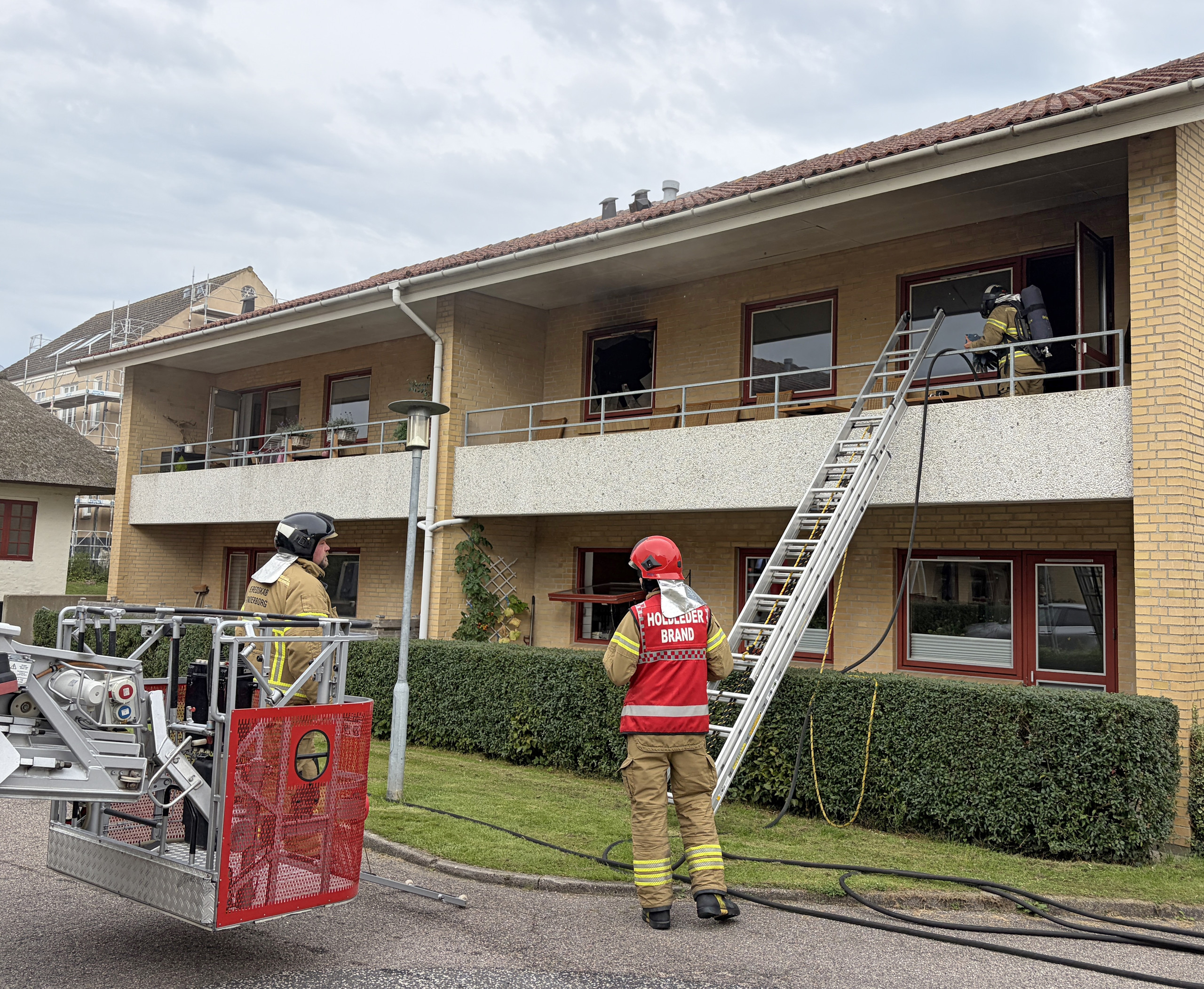 Tre på skadestuen efter voldsom brand (1) Brandfolk med stige ved en sodsværtet altan i Domhusparken i Gråsten